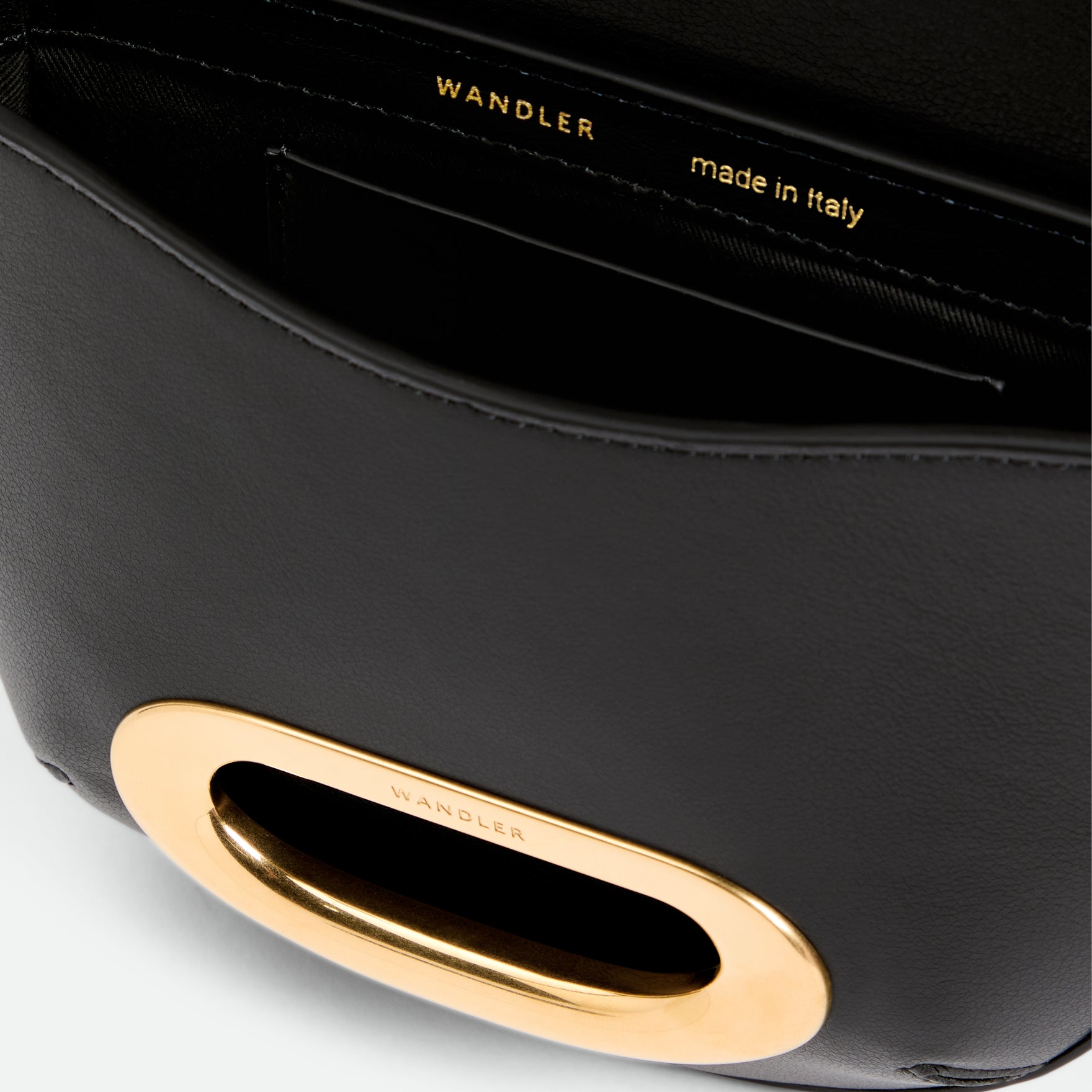 Wandler Veneto Crossbody Small in Black, made from Italian calf leather with golden clasp hardware and structured silhouette, close up detailing the clasp, leather, with a small glimpse into the inside of the bag. 
