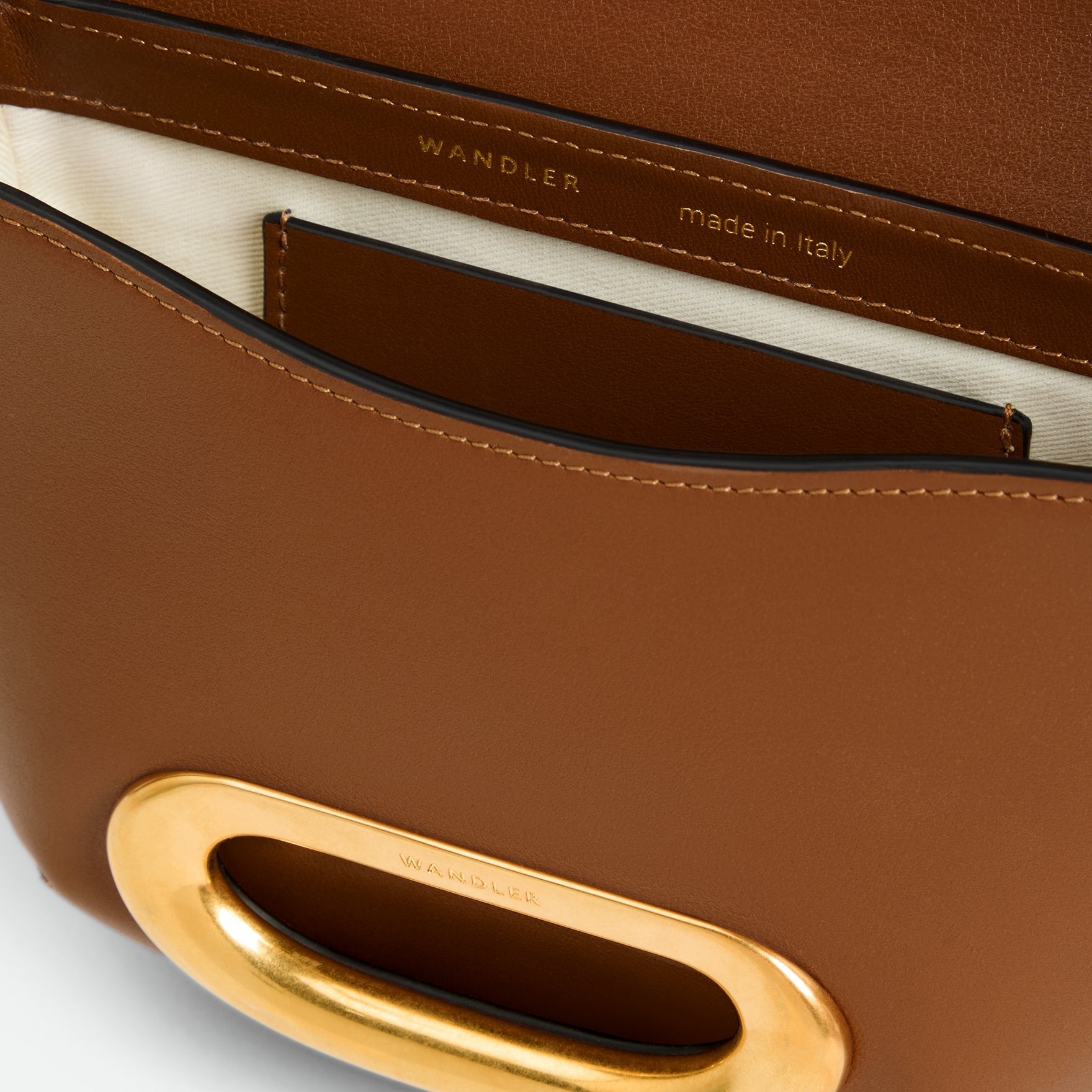 Wandler Veneto Crossbody Small in Saddle, warm brown, made from Italian calf leather with golden clasp hardware and structured silhouette, close up detailing the clasp, leather, with a small glimpse into the inside of the bag. 
