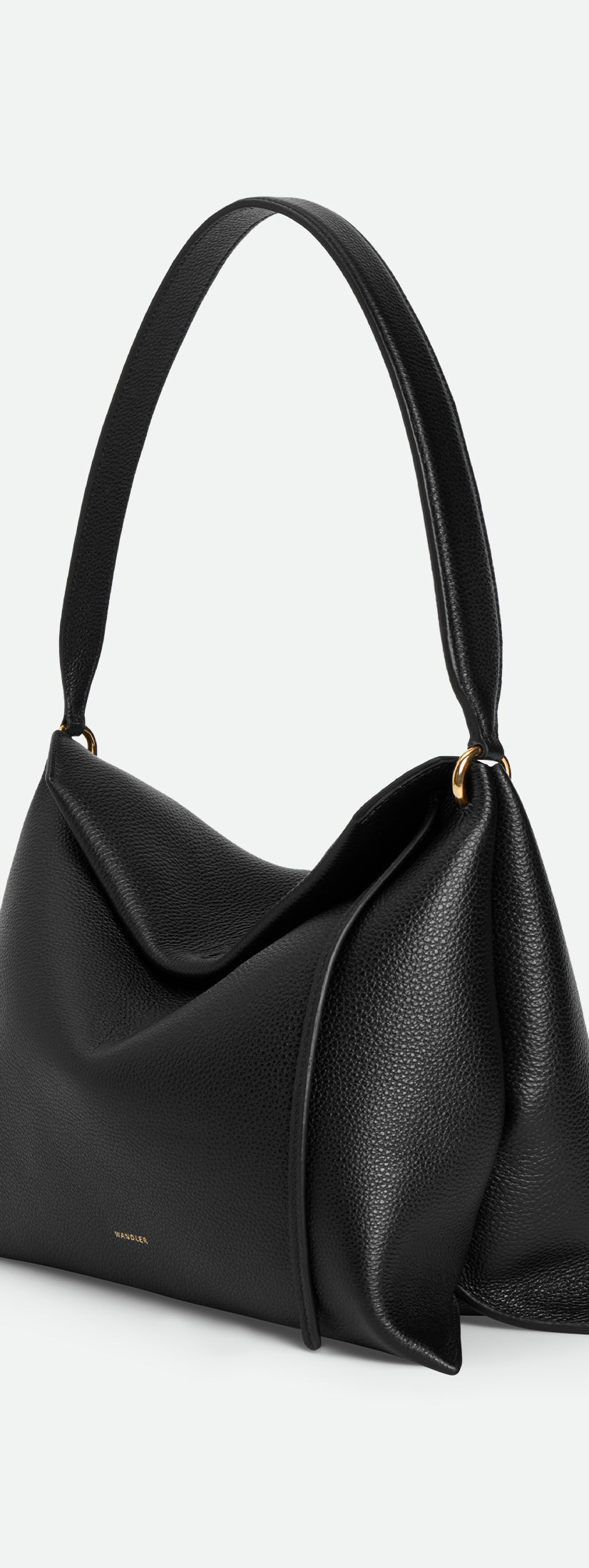 Wandler Penelope Tote Small in the color Black Crust made from calf leather with golden hardware and soft slouchy silhouette, side view.