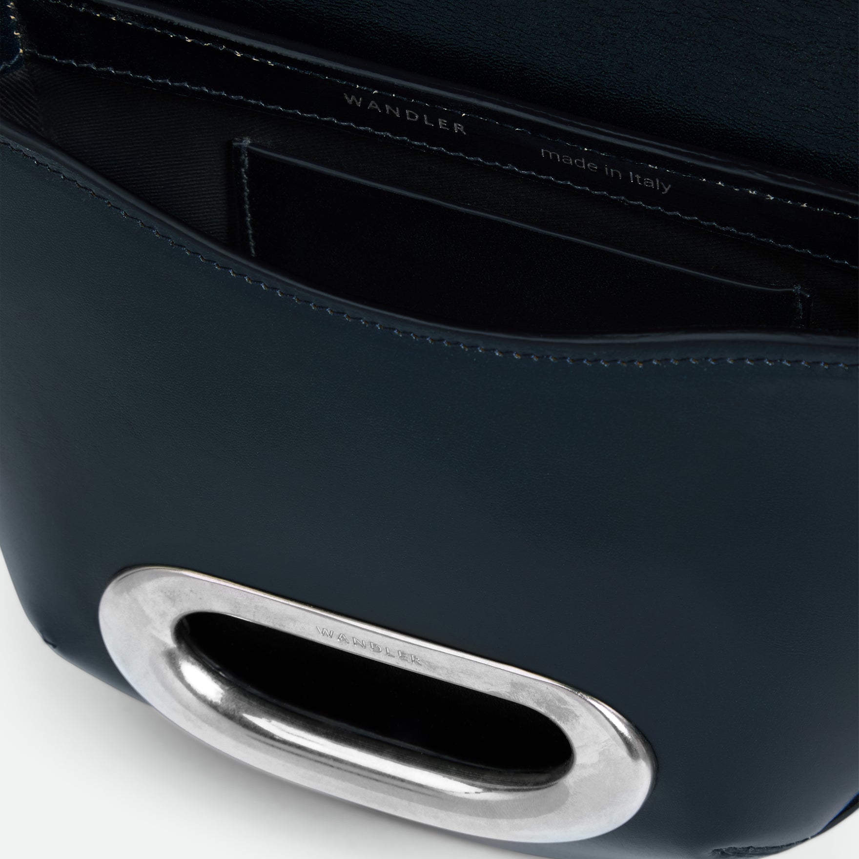 Wandler Veneto Crossbody Small in Orion Glaze, deep dark blue, Italian calf leather with silver clasp hardware and structured silhouette, close up detailing the clasp,  leather, with a small glimpse into the inside of the bag. 