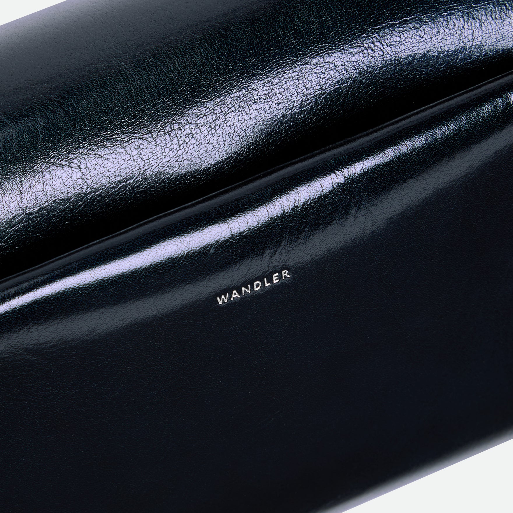 
Wandler Veneto Shoulder Bag in the color Orion Glaze, deep dark blue, Italian calf leather with oversized silver clasp hardware and structured silhouette, close up shot of the logo and leather. 