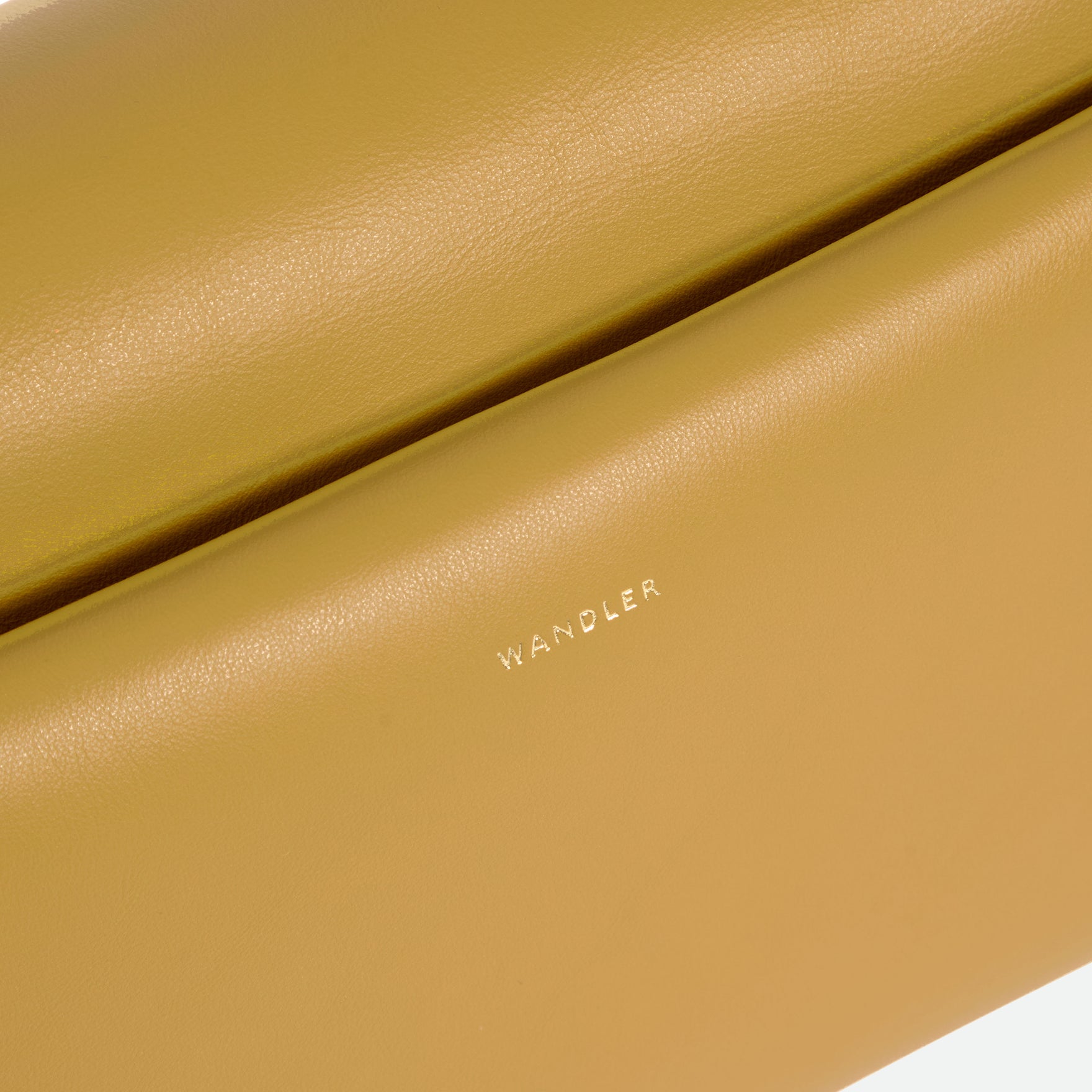 Wandler Veneto Shoulder Bag in the color Saffron, yellow, Italian calf leather with oversized golden clasp hardware and structured silhouette, closeup detailing the logo and leather. 