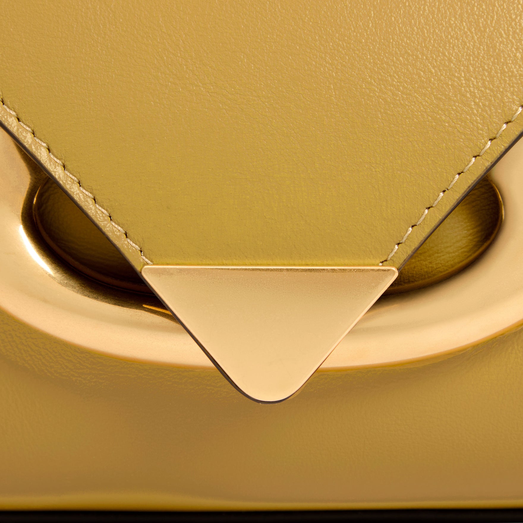 Wandler Veneto Shoulder Bag in the color Saffron, yellow, Italian calf leather with oversized golden clasp hardware and structured silhouette, close up detailing the clasp and the leather. 