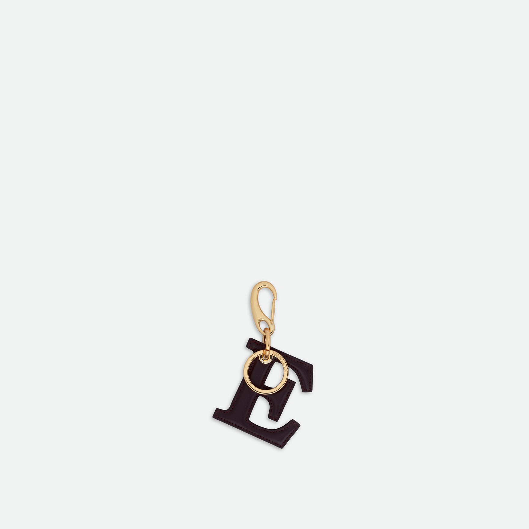 Wandler Bag Charm Letter in the color Grape, deep dark purple, made from brass and lambskin leather with golden hardware, shown on its own against a white background, backside view. 