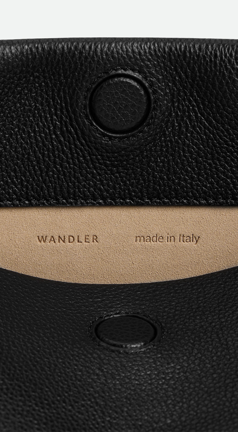 Wandler Penelope Tote Small in the color Black Crust made from calf leather with golden hardware and soft slouchy silhouette, close up detailing the closure and leather.