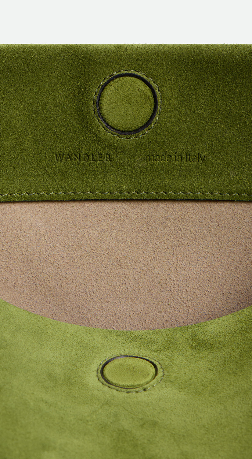 Wandler Penelope Tote Small in the color Verde Suede / Black made from calf leather with golden hardware and soft slouchy silhouette, close up detailing the closure and leather.