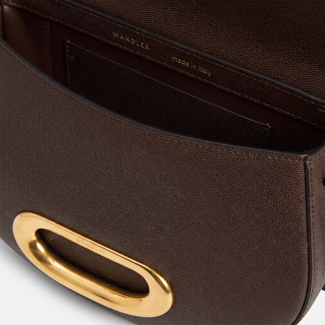 Wandler Veneto Crossbody Bag in Soil Caviar calf leather with oversized golden clasp hardware and structured silhouette, pictured from above with the flap open, giving a glimpse of the inside. 