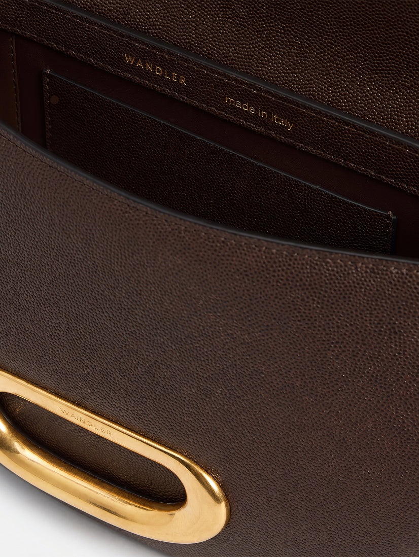 Wandler Veneto Crossbody Bag in Soil Caviar calf leather with oversized golden clasp hardware and structured silhouette, pictured from above with the flap open, giving a glimpse of the inside. 