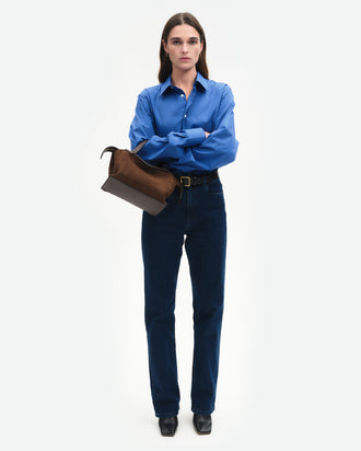 Wandler Ida Bag in Palissander Suede, deep dark brown with red undertones, Italian calf leather with golden hardware and sculptural top handle, pictured on model wearing the bag on the forearm, front view.