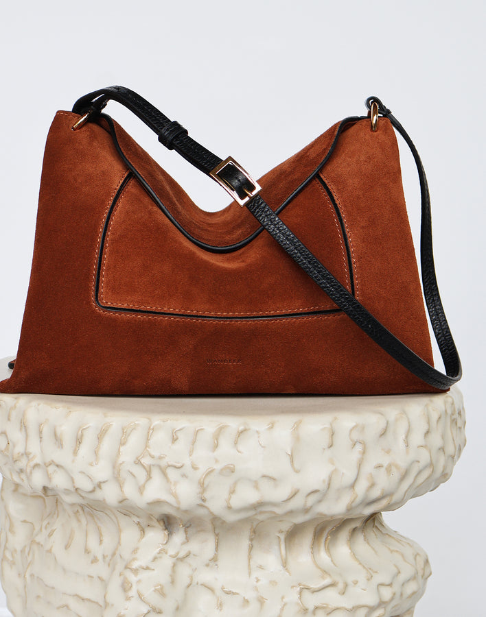 Wandler Penelope Slouch Bag in the color Saddle Suede, made from calf leather with golden hardware and adjustable slim strap, pictured on pillar.