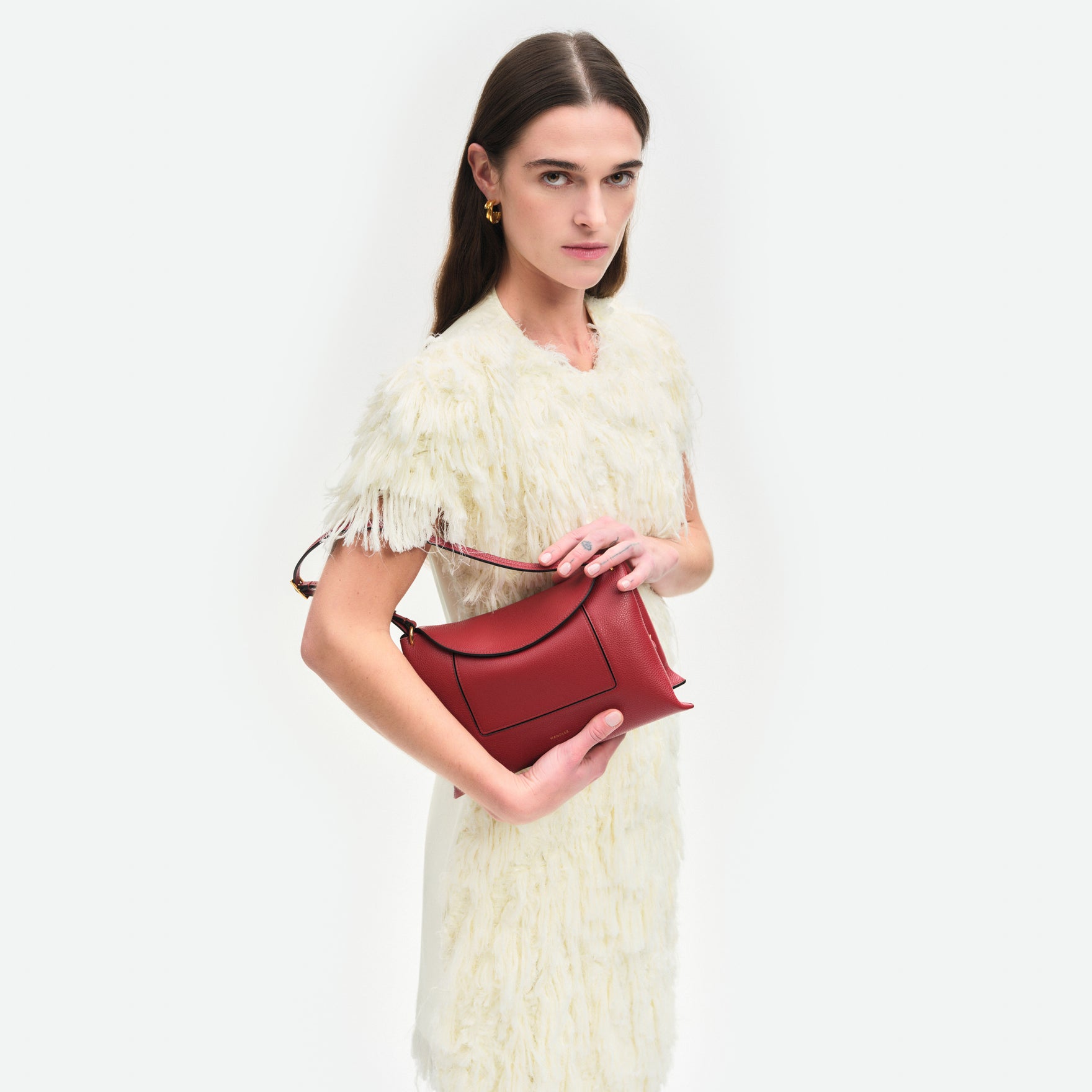 Wandler Penelope Slouch Bag in the color Scarlet Crust, made from calf leather with golden hardware and adjustable slim strap, pictured being held in the hand by model, half body picture.