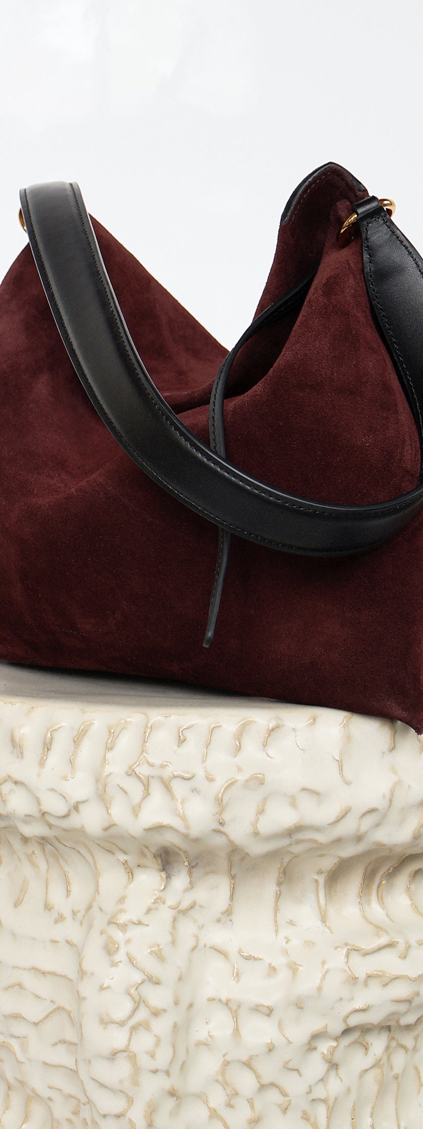 Wandler Penelope Tote Small in the color Acai Suede / Black made from calf leather with golden hardware and soft slouchy silhouette, front view, pictured on pillar.