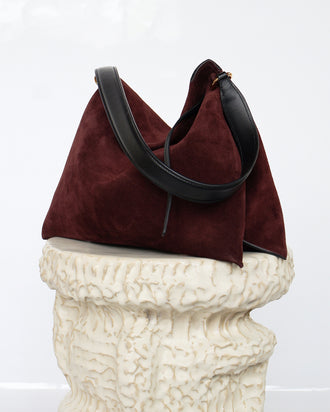 Wandler Penelope Tote Small in the color Acai Suede / Black made from calf leather with golden hardware and soft slouchy silhouette, front view, pictured on pillar.