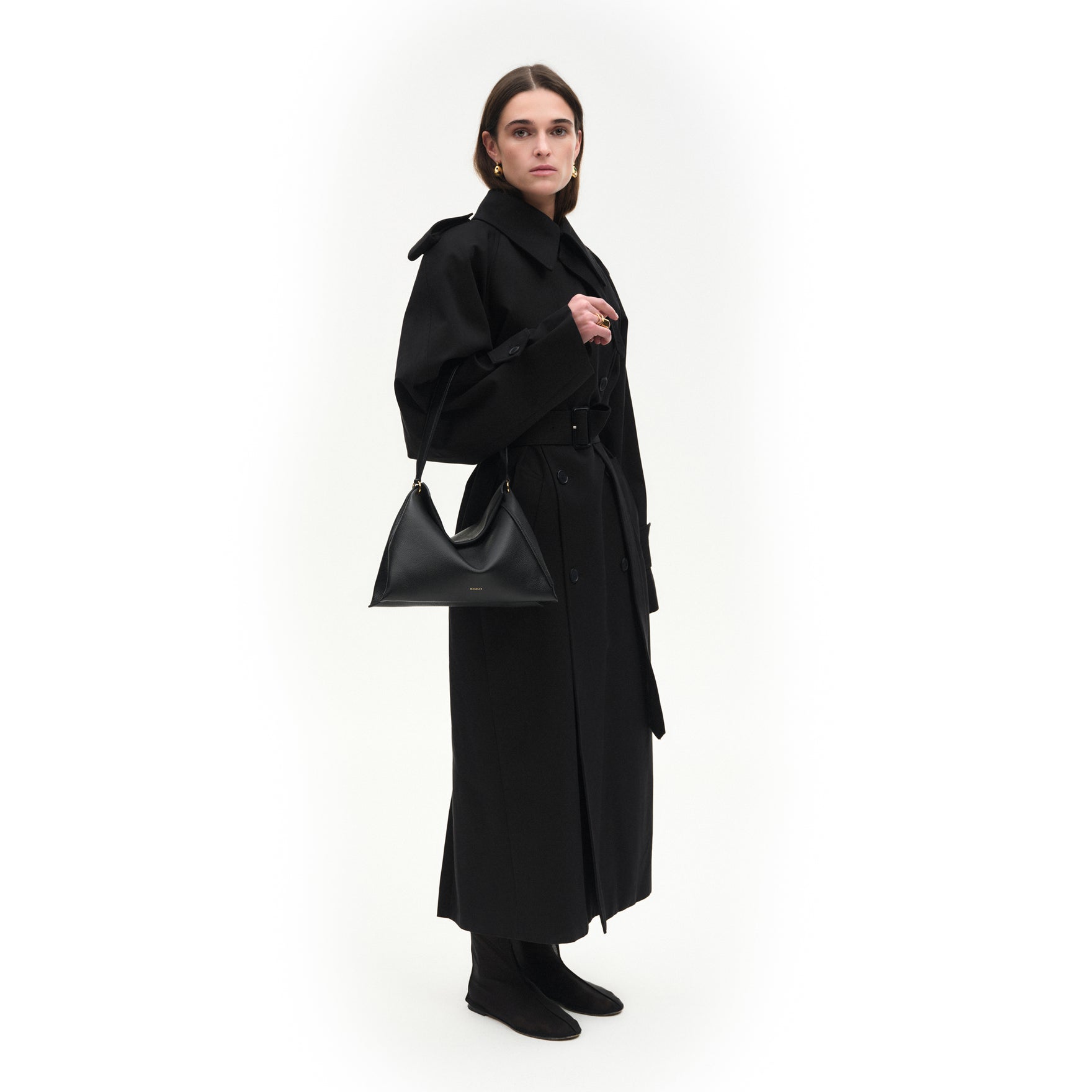 Wandler Penelope Tote Small in the color Black Crust made from calf leather with golden hardware and soft slouchy silhouette, pictured being worn on the fore arm by model, full body picture.