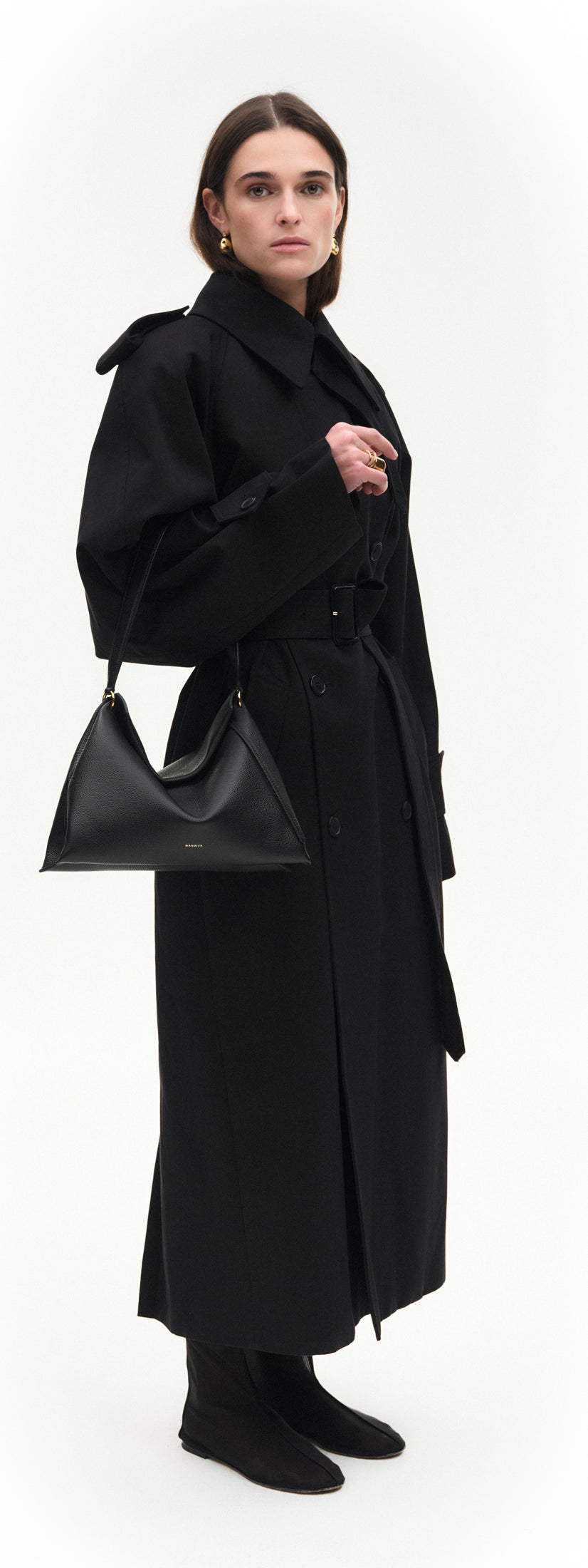 Wandler Penelope Tote Small in the color Black Crust made from calf leather with golden hardware and soft slouchy silhouette, pictured being worn on the fore arm by model, full body picture.