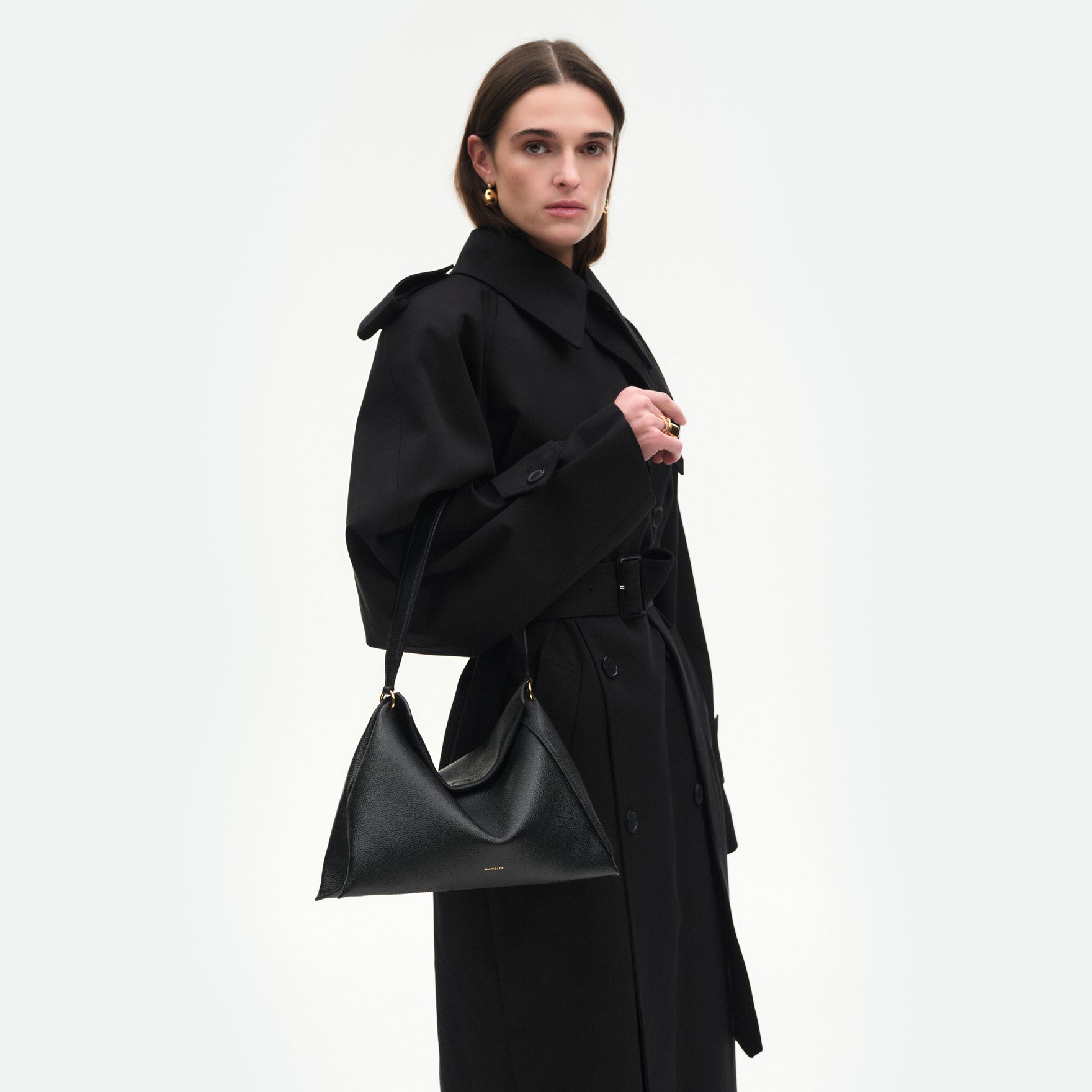 Wandler Penelope Tote Small in the color Black Crust made from calf leather with golden hardware and soft slouchy silhouette, pictured being worn on the fore arm by model, half body picture.