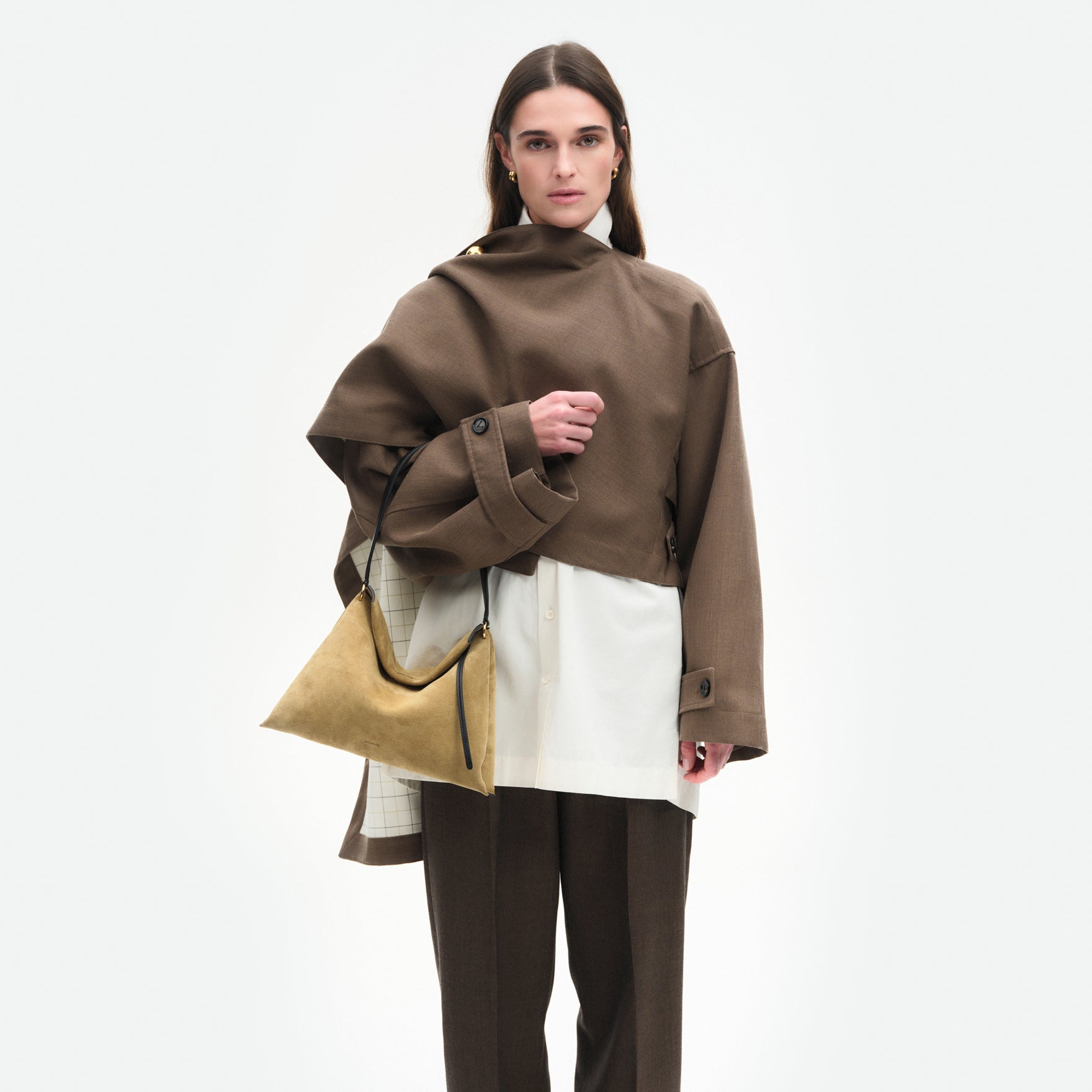 Wandler Penelope Tote Small in the color Khaki Suede / Black made from calf leather with golden hardware and soft slouchy silhouette, pictured being worn by model on the forearm, half body picture.