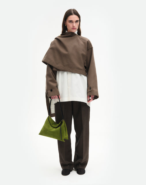 Wandler Penelope Tote Small in the color Verde Suede / Black made from calf leather with golden hardware and soft slouchy silhouette, pictured being hand carried by model, full body picture.