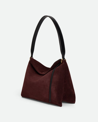 Wandler Penelope Tote Small in the color Acai Suede / Black made from calf leather with golden hardware and soft slouchy silhouette, three quarters view with the straps suspended into the air.