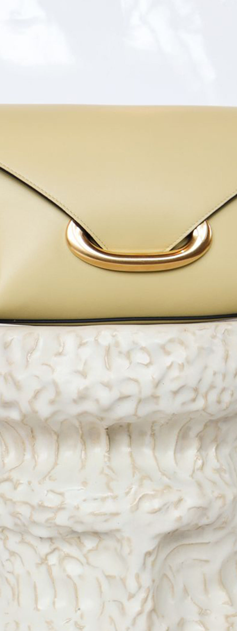 Wandler Veneto Shoulder Bag Small in the color Island, made from Italian calf leather with oversized golden clasp hardware, structured silhouette, pictured on pillar.