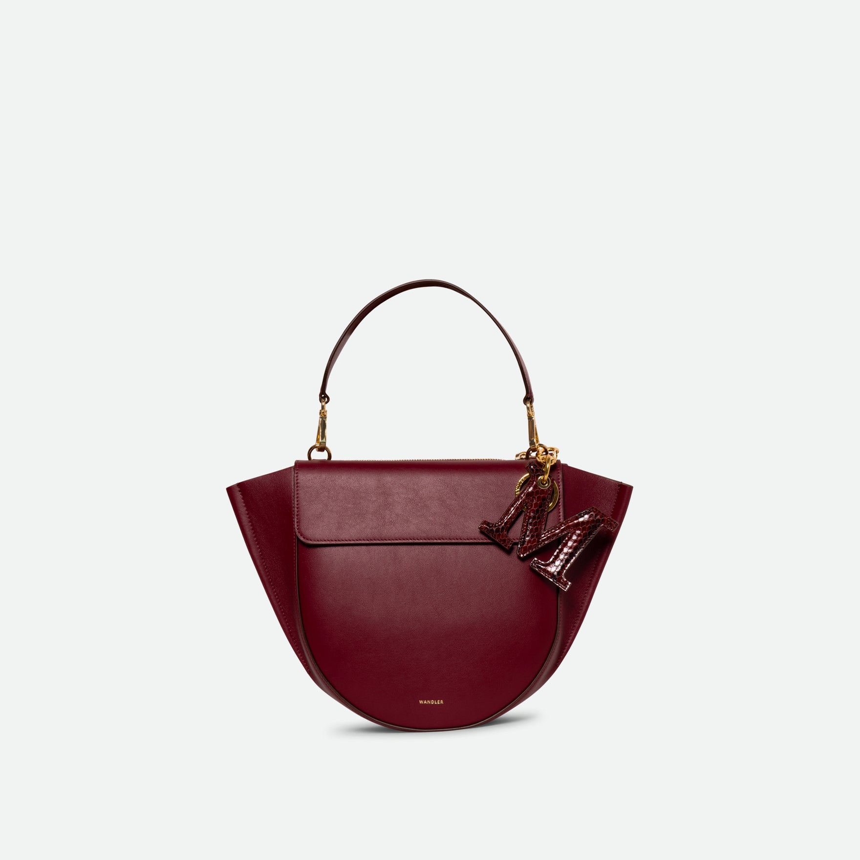 Wandler Bag Charm Letter in the color Bordeaux Python, bordeaux red with python motive, made from brass, lambskin leather with golden hardware, shown attached to a bag, front view.