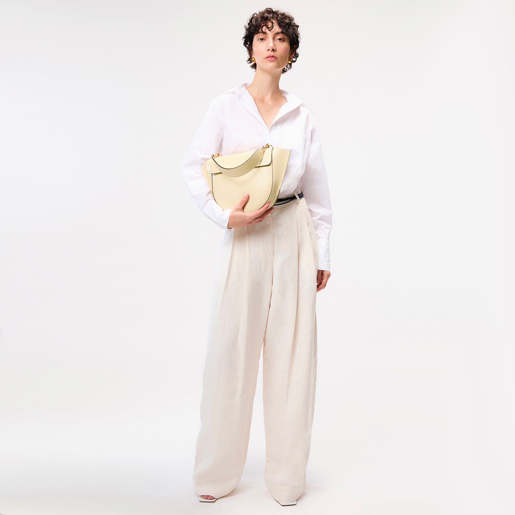 Wandler Hortensia Bag Medium in the color Shell, Italian calf leather with golden hardware, rounded silhouette and top handle, pictured being held in the hand by model.