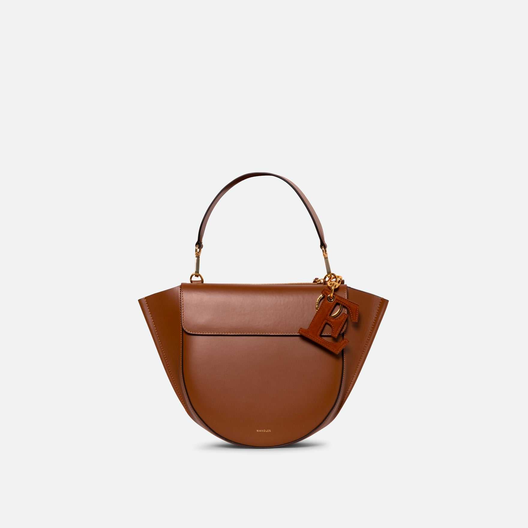Wandler Bag Charm Letter in the color Tan Suede, caramel brown, letter E, made from brass, suede lambskin leather with golden hardware, shown attached to a bag, front view.