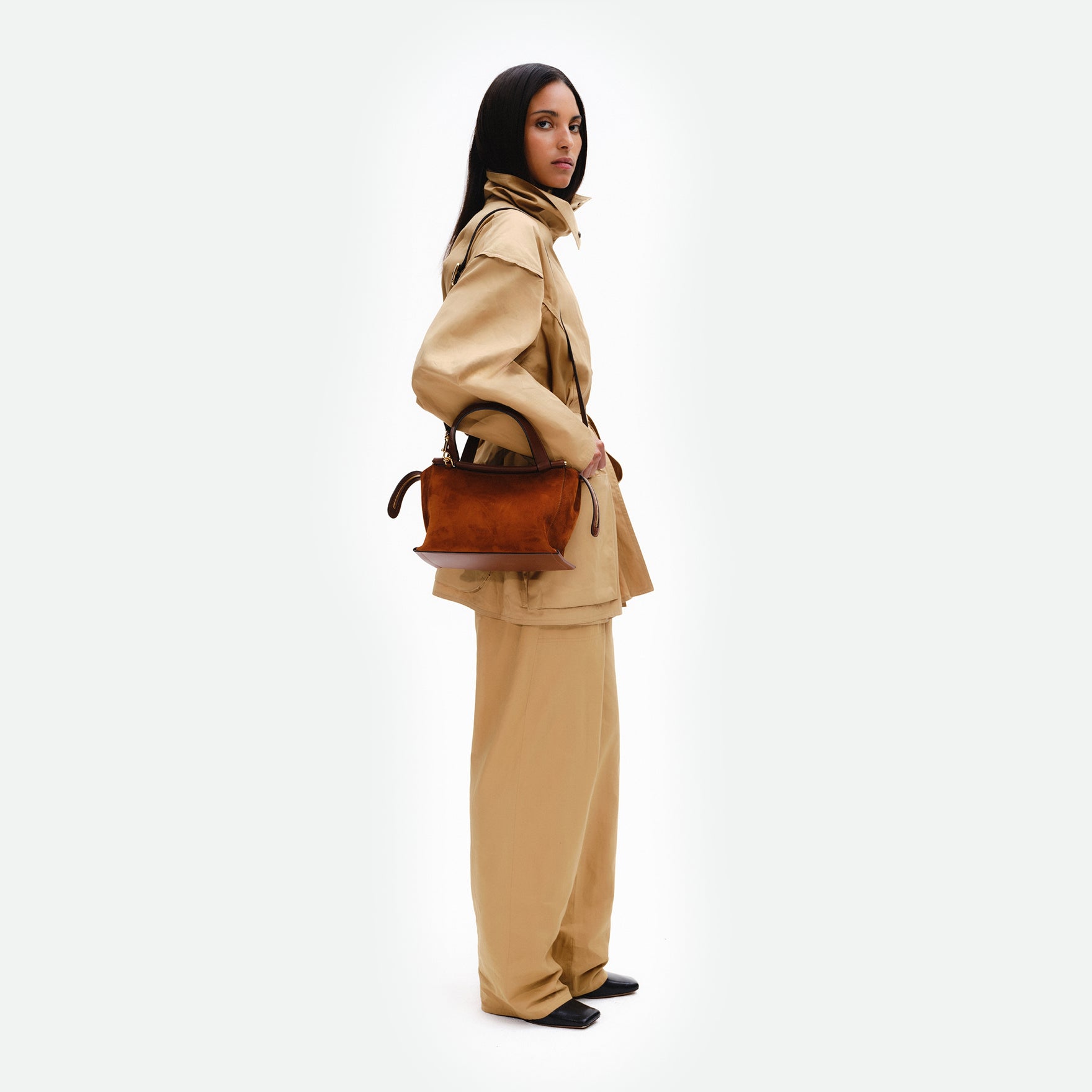 Wandler Ida Bag in the color Tan Suede, made from Italian calf leather with golden hardware and sculptural top handle, pictured being worn on the shoulder by model.
