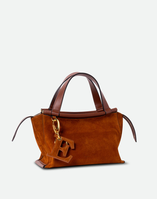 Wandler Bag Charm Letter in the color Tan Suede, caramel brown, letter E, made from brass, suede lambskin leather with golden hardware, shown attached to a bag with matching suede material, front view.