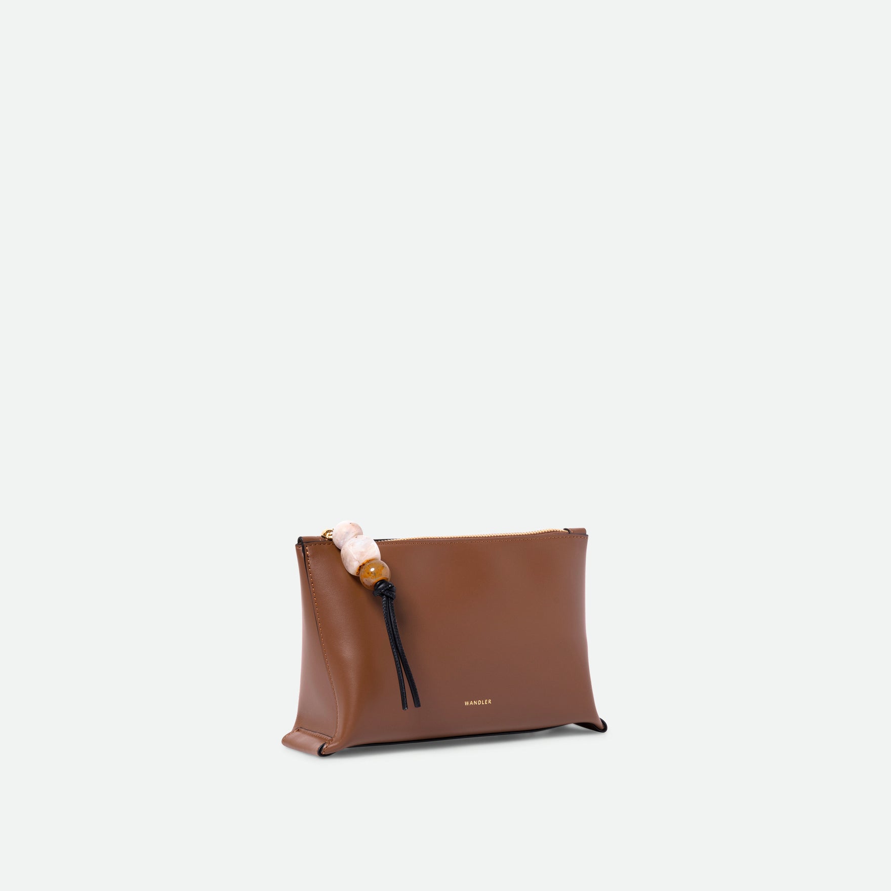 Wandler Ida Case in Saddle, made from calf leather with golden zipper hardware and charm, three quarters view.