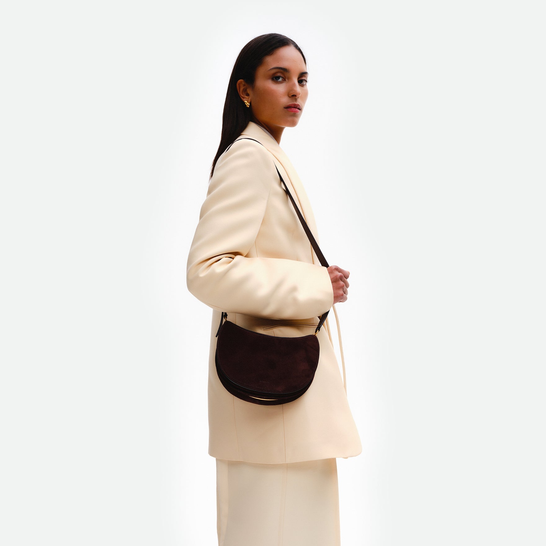 Wandler Kate Bag in the color Acai Suede, made from calf leather with golden hardware and adjustable shoulder strap, pictured on model, worn on the shoulder.