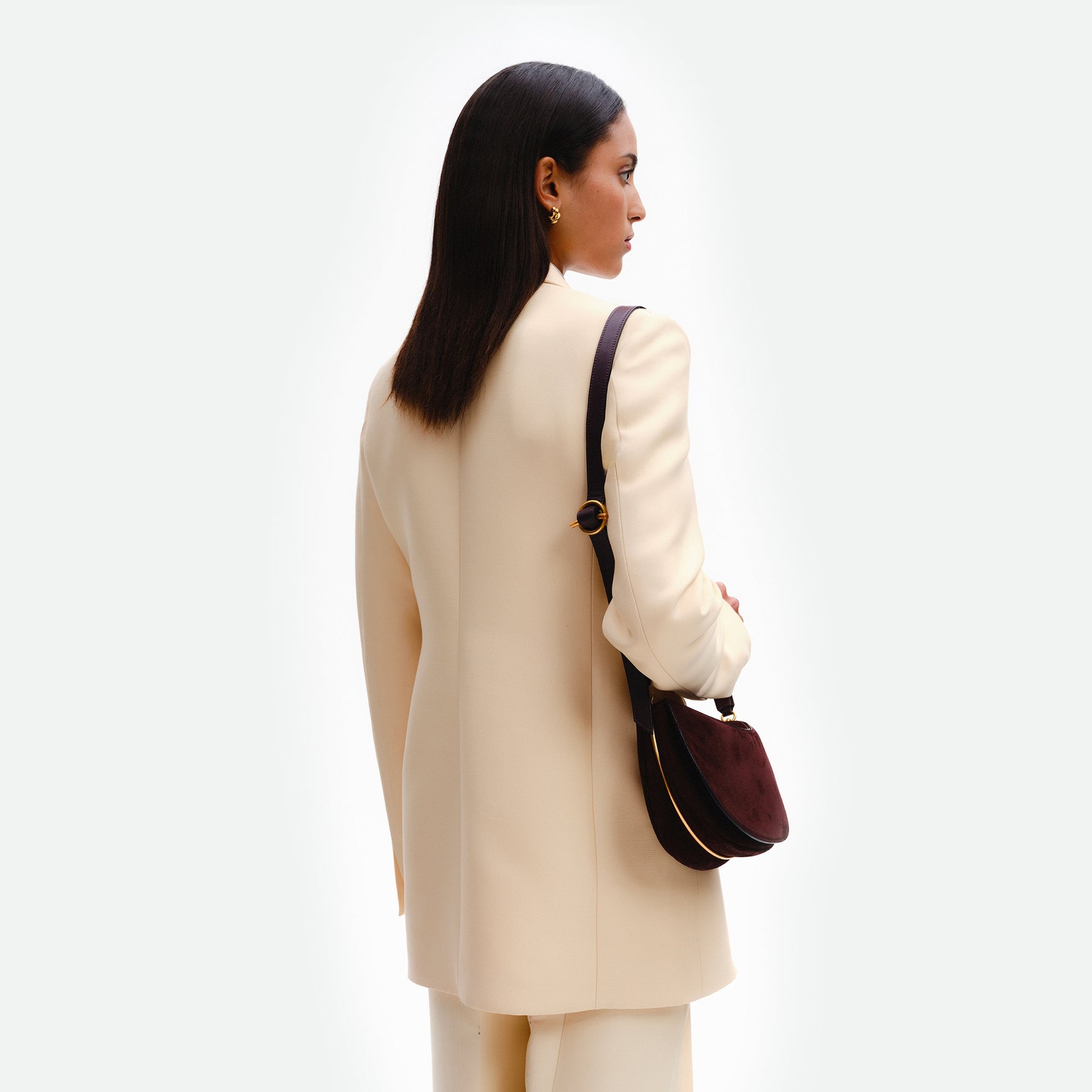 Wandler Kate Bag in the color Acai Suede, made from calf leather with golden hardware and adjustable shoulder strap, pictured on model, being worn on the shoulder.
