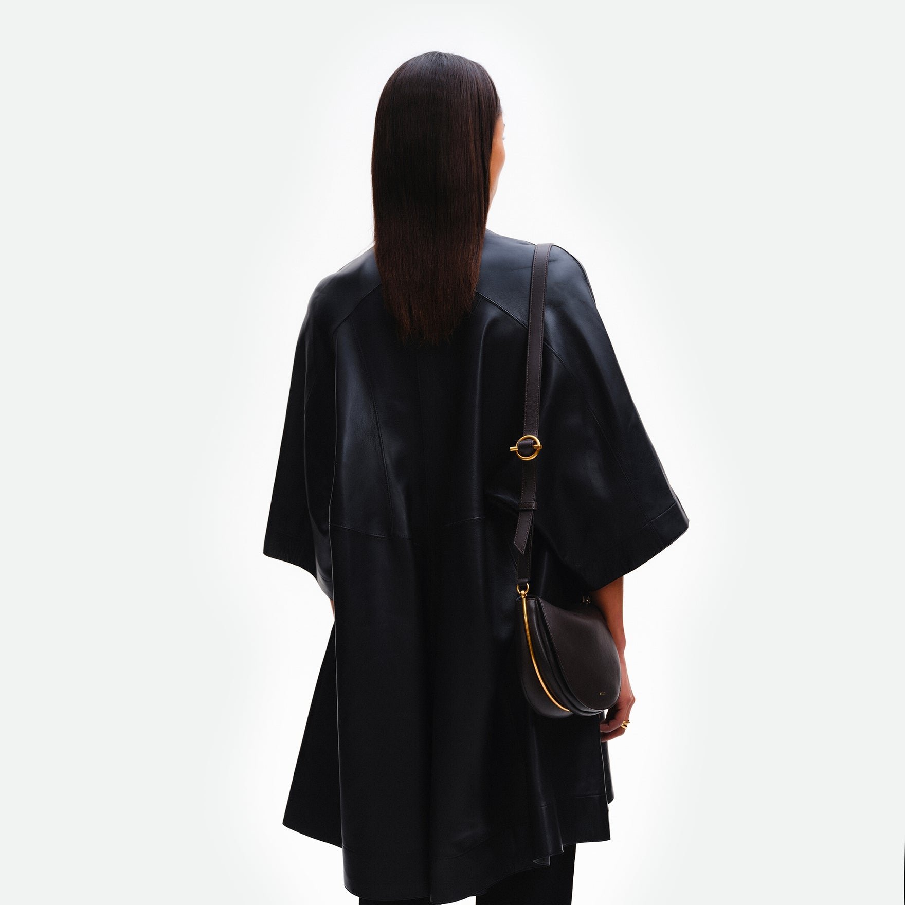 Wandler Kate Bag in the color Black, made from Italian calf leather with golden hardware and adjustable shoulder strap, pictured on model, worn on the shoulder, half body picture. 