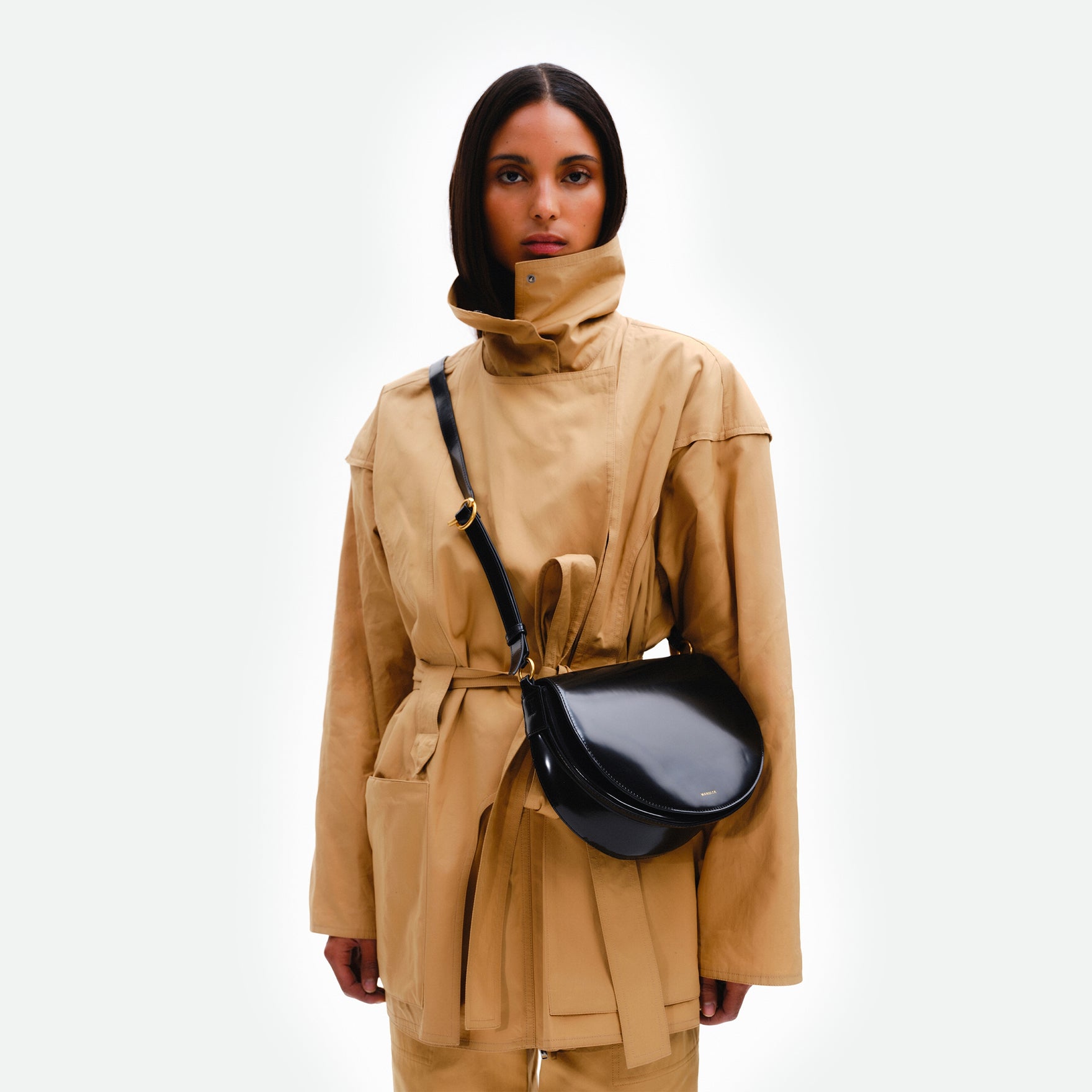 Wandler Kate Saddle Bag in the color Jazz Olive, deep dark green, calf leather with golden hardware and adjustable shoulder strap, pictured on model, worn in crossbody style.