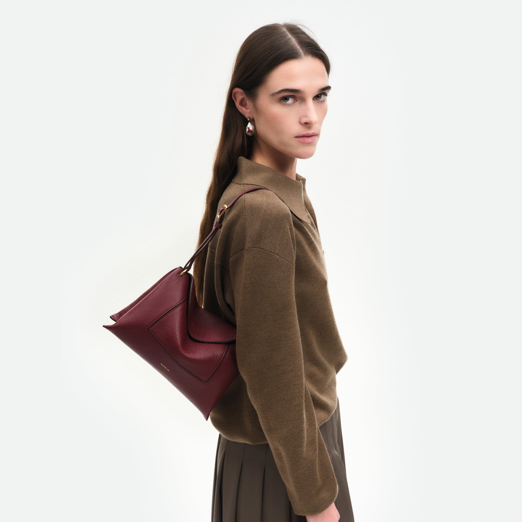 Wandler Penelope Slouch Bag in the color Acai Crust, deep dark red, made from smooth calf leather with golden hardware and adjustable slim strap, pictured being worn by model on the shoulder.