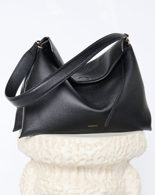 Wandler Penelope Tote Small in the color Black Crust made from calf leather with golden hardware and soft slouchy silhouette, pictured on pillar.