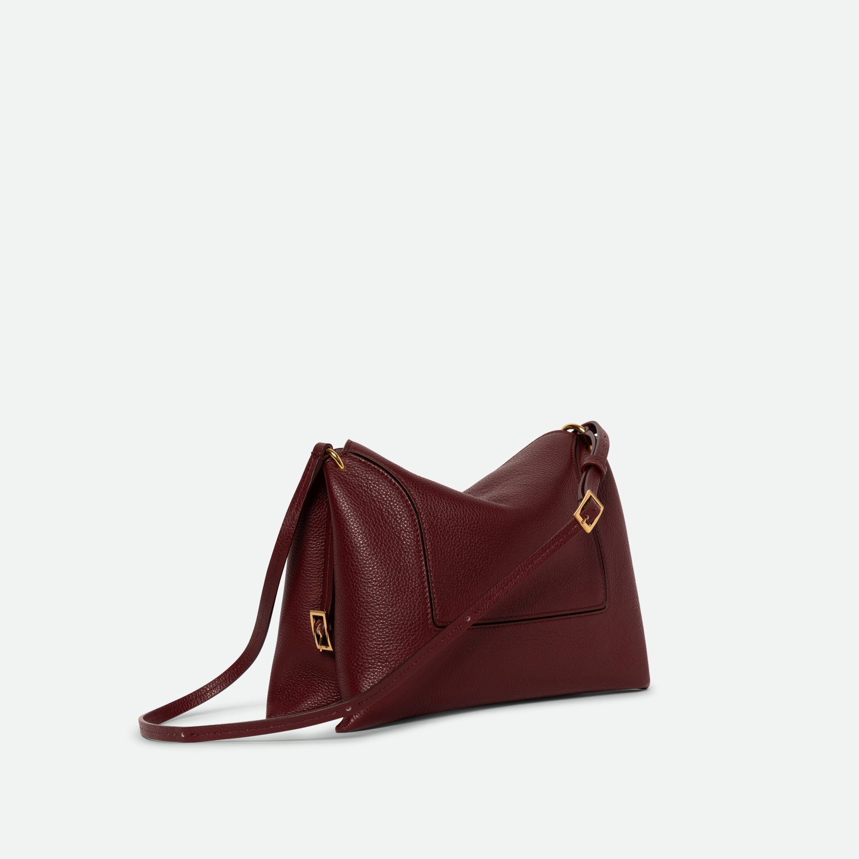 Wandler Penelope Slouch Bag in the color Acai Crust, deep dark red, made from smooth calf leather with golden hardware and adjustable slim strap, three quarters view.