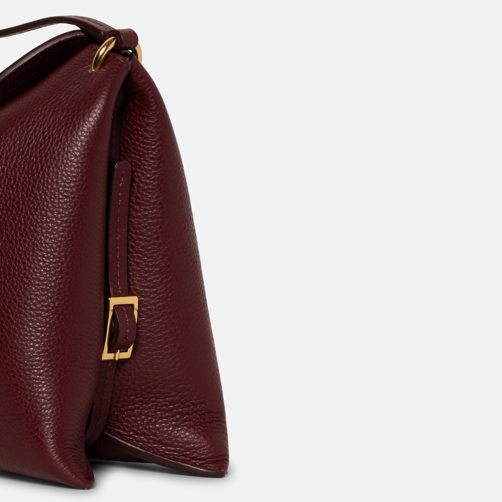 Wandler Penelope Slouch Bag in the color Acai Crust, deep dark red, made from smooth calf leather with golden hardware and adjustable slim strap close up of the leather and buckle with strap, close up detailing the buckle and leather of the bag. 