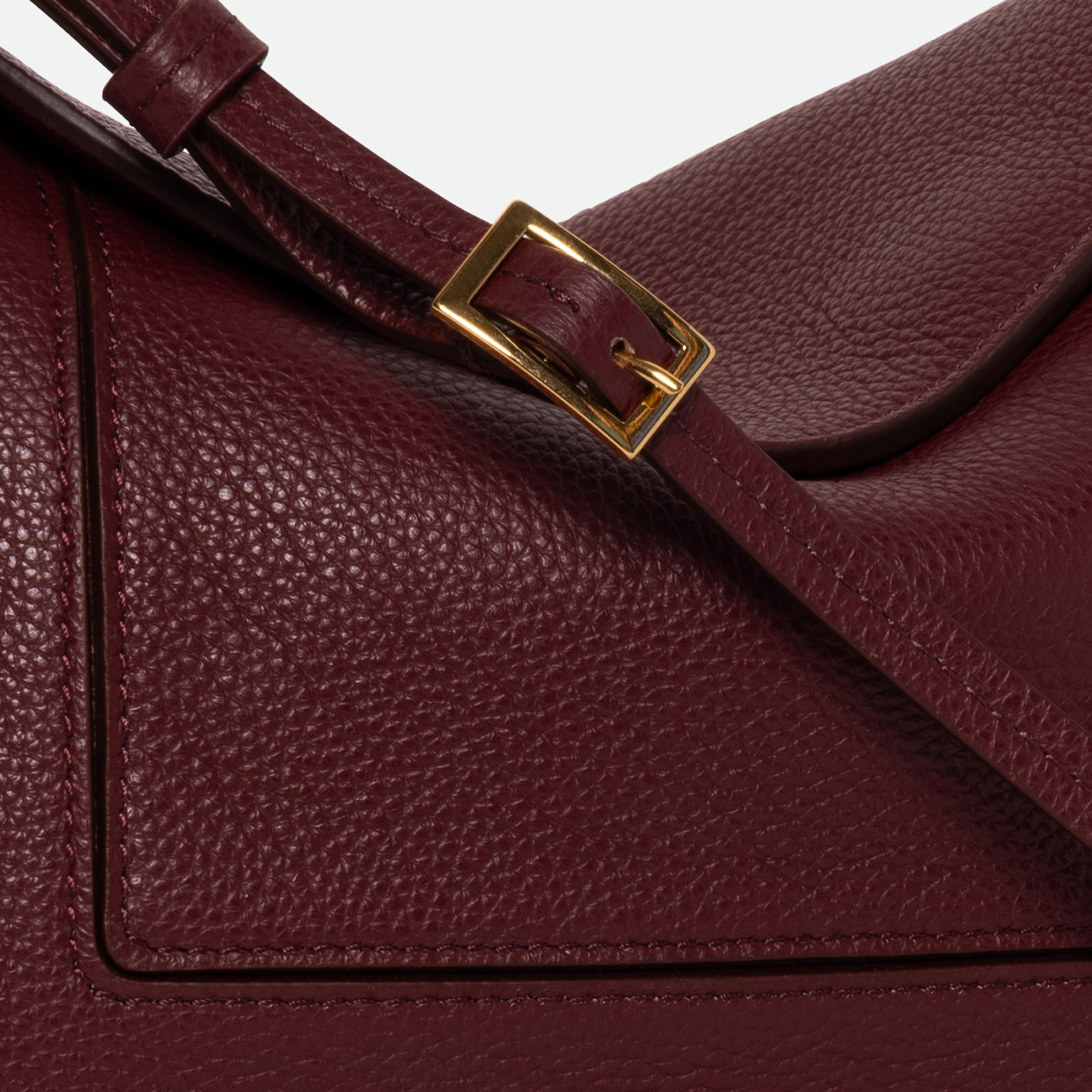 Wandler Penelope Slouch Bag in the color Acai Crust, deep dark red, made from smooth calf leather with golden hardware and adjustable slim strap close up of the leather and buckle with strap.
