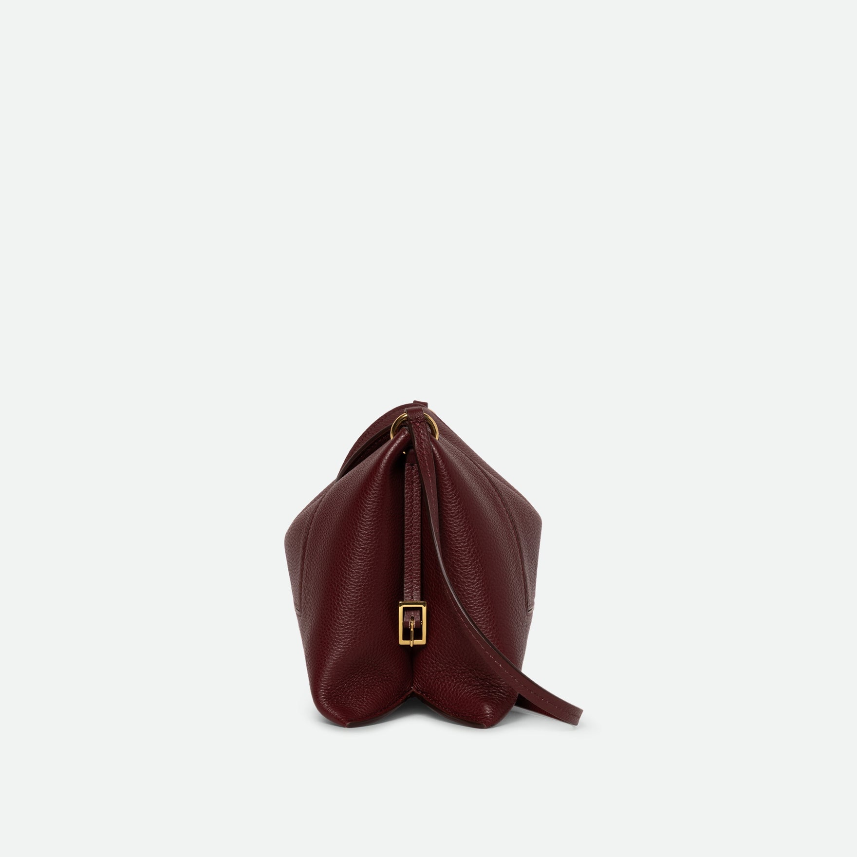 Wandler Penelope Slouch Bag in the color Acai Crust, deep dark red, made from smooth calf leather with golden hardware and adjustable slim strap close up of the leather and buckle with strap, side view.