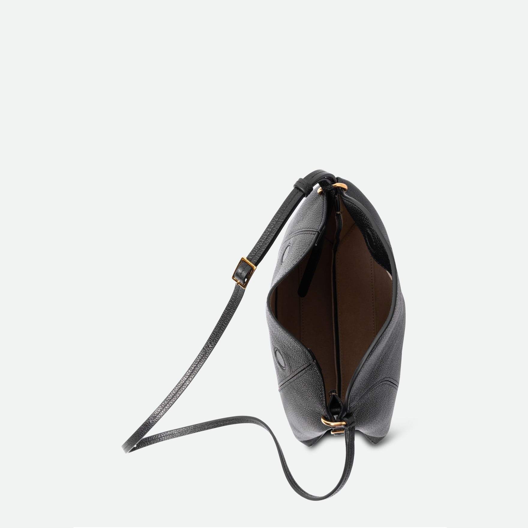 Wandler Penelope Slouch Bag in the color Black Crust, made from smooth calf leather with golden hardware and adjustable slim strap, pictured from above with the flap open, giving a glimpse of the inside of the bag. 
