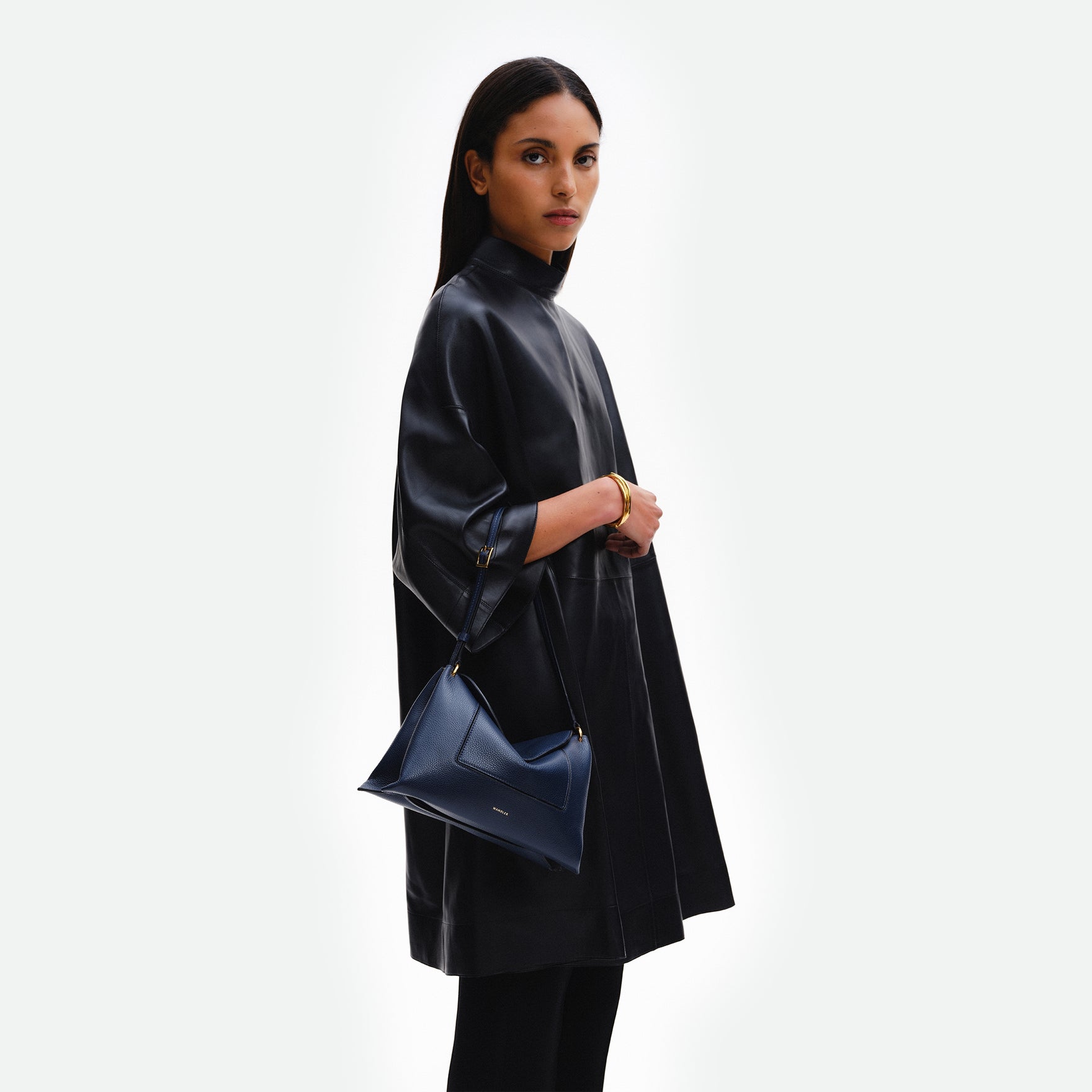 Wandler Penelope Slouch Bag in the color Orion Crust deep dark blue, made from calf leather with golden hardware and adjustable slim strap, pictured on model, worn on the forearm. 