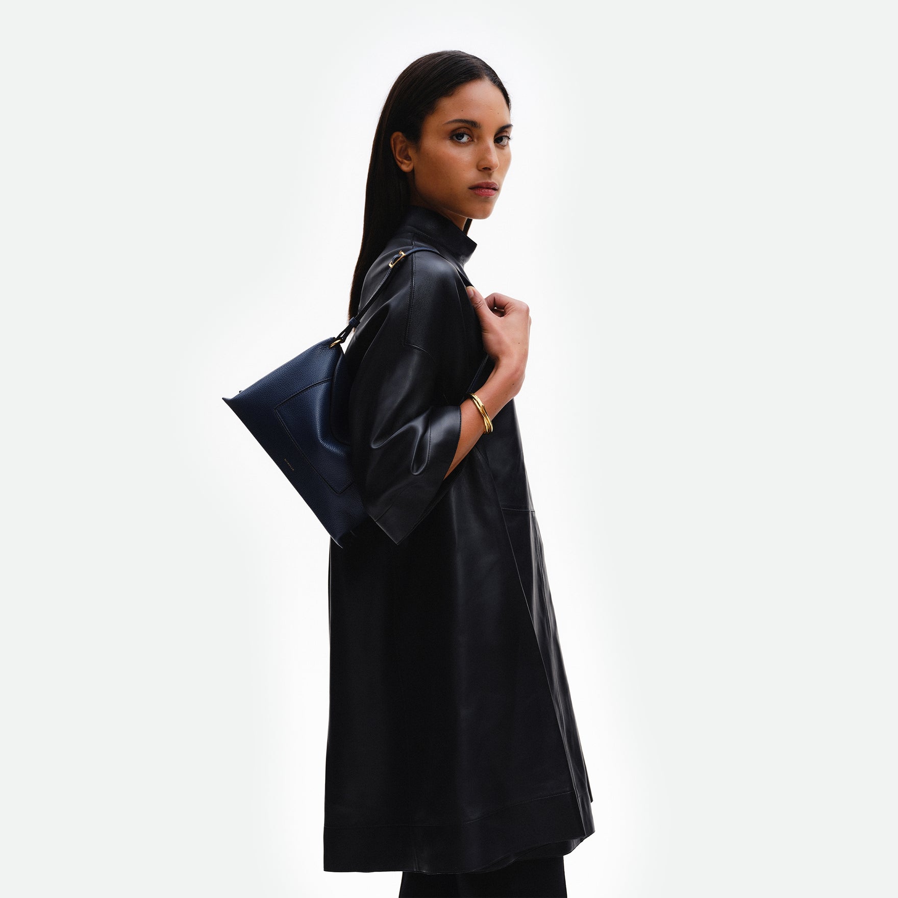 Wandler Penelope Slouch Bag in the color Orion Crust deep dark blue, made from calf leather with golden hardware and adjustable slim strap, pictured on model, worn on the shoulder, half body picture. 