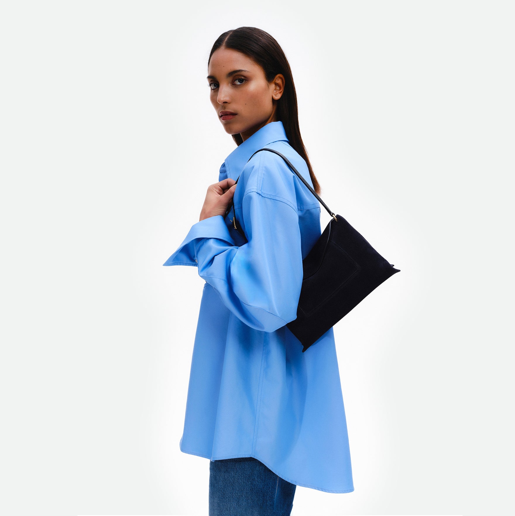 Wandler Penelope Slouch Bag in the color Orion Suede, deep dark blue, made from calf leather with golden hardware and adjustable slim strap, pictured on model, worn on shoulder. 