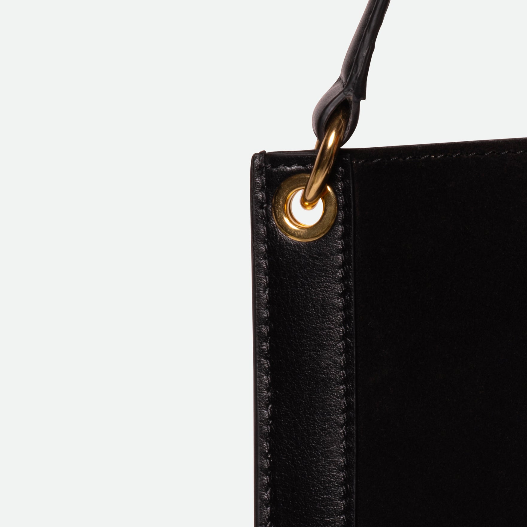 Wandler Penny Tote in the color Black Suede, made from Italian calf leather with hand-painted black edges and golden hardware, close up detailing leather and strap attachment.