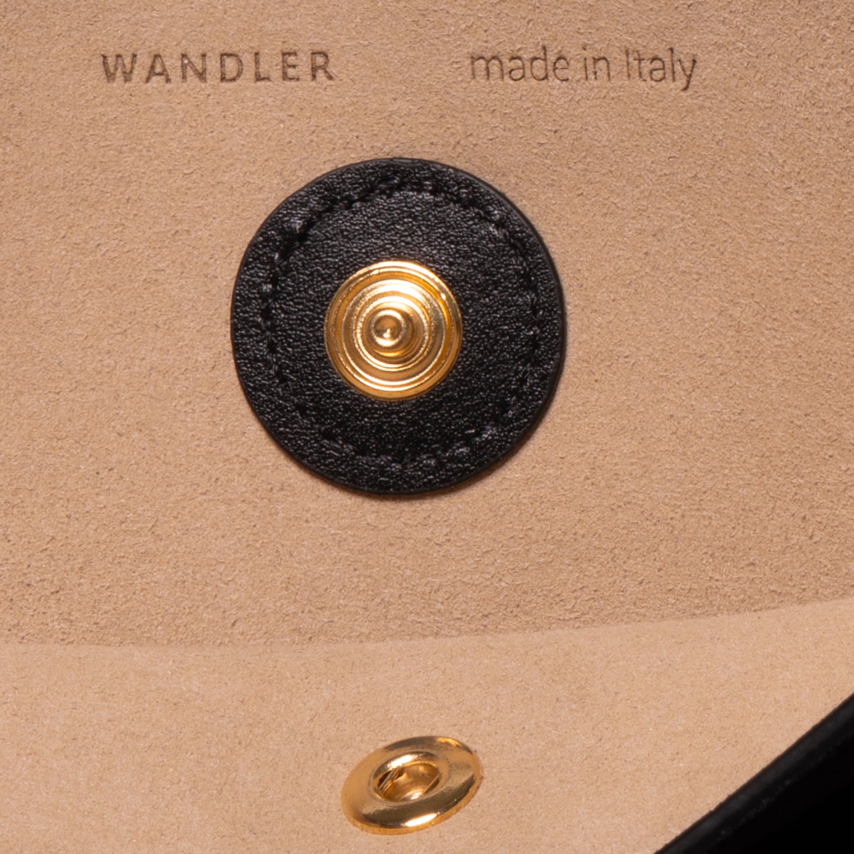 Wandler Penny Tote in the color Black Suede, made from Italian calf leather with hand-painted black edges and golden hardware, close up detailing button closure.