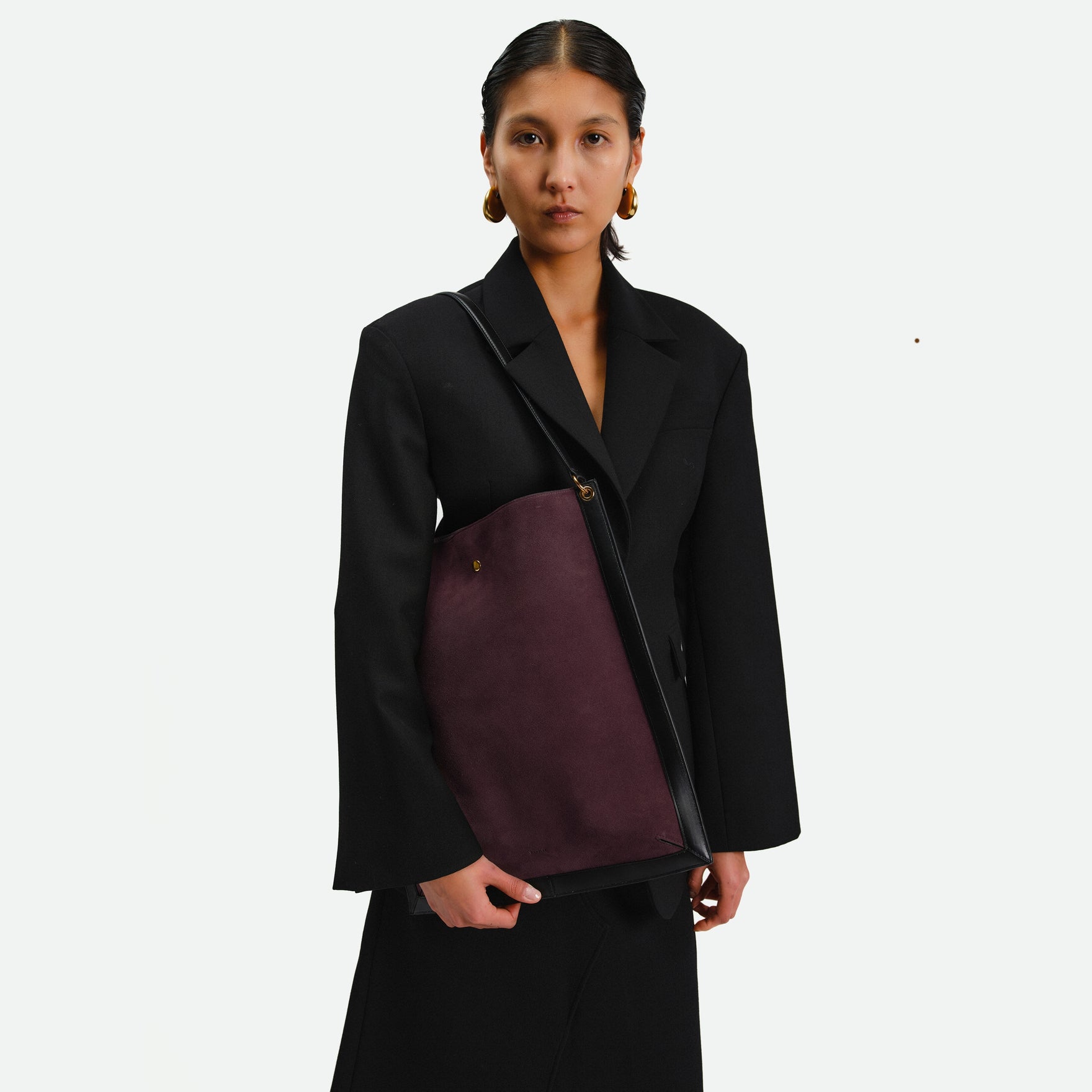 Wandler Penny Tote in the color Grape, made from Italian calf leather with hand-painted black edges and golden hardware, pictured on model being worn on the shoulder.