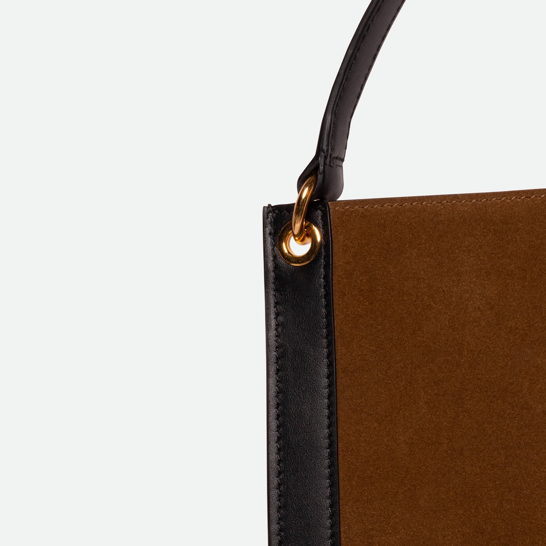 Wandler Penny Tote in the color Tabacco Suede, made from Italian calf leather with hand-painted black edges and golden hardware, close up detailing the leather and strap attachment.