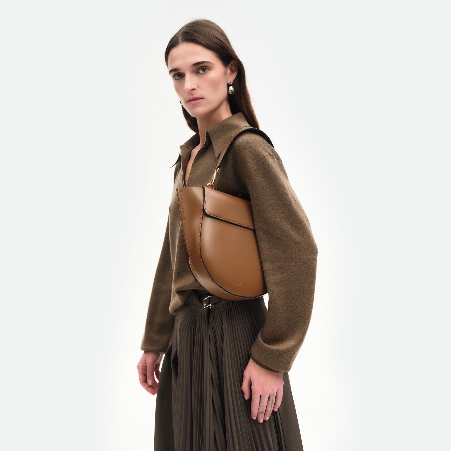 Wandler Hortensia Bag Medium in the color Saddle, warm brown, made from Italian calf leather with golden hardware, rounded silhouette and top handle, pictured on model, being worn on the shoulder, half body picture. 