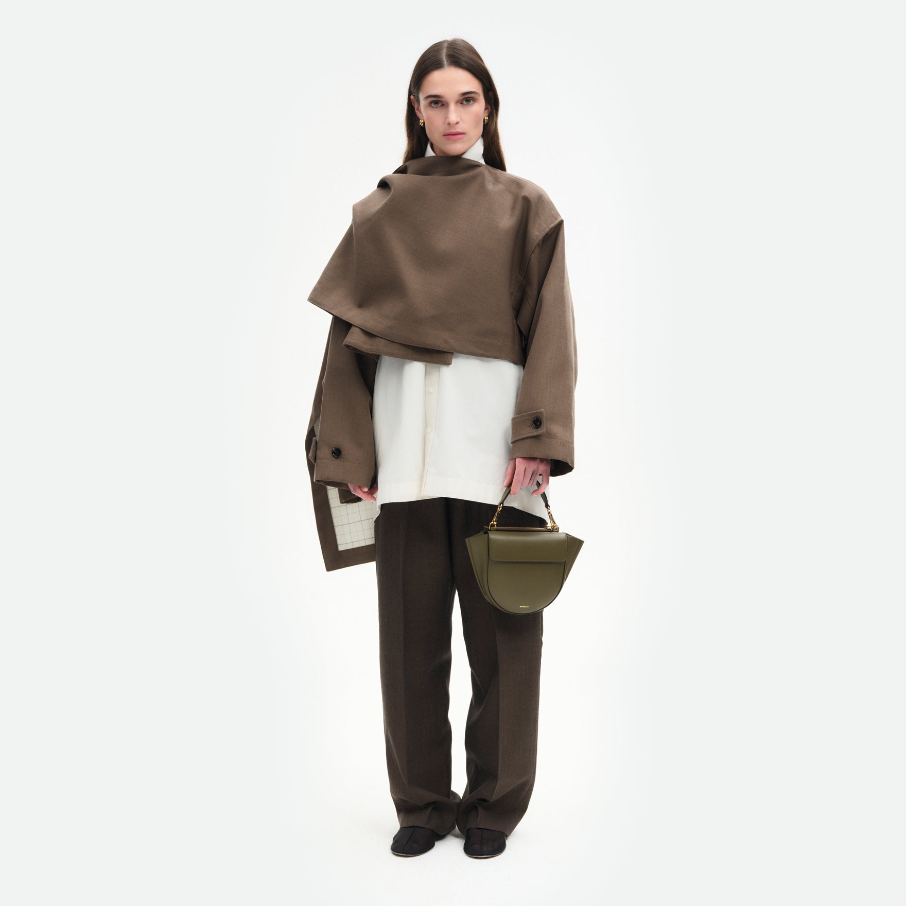 Wandler Hortensia Bag Mini in the color Deep Olive, Olive green, made from Italian calf leather with golden hardware, rounded silhouette and top handle, pictured on model, being handheld, full body picture. 